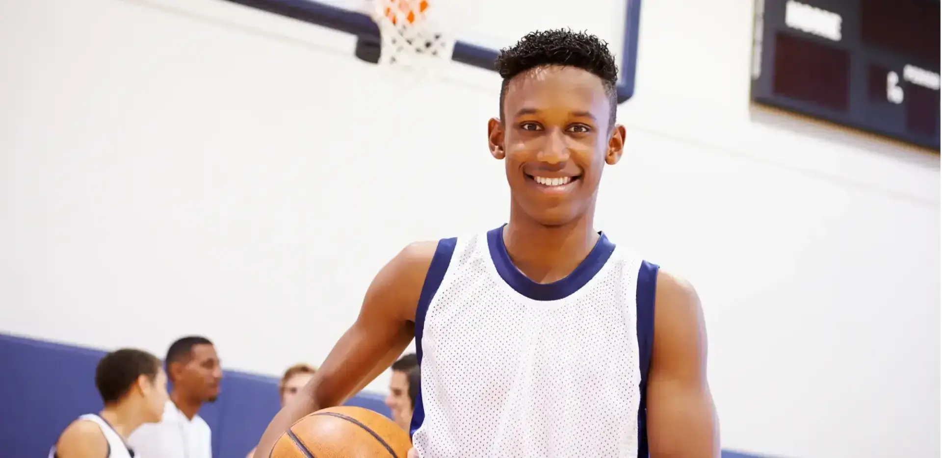 Student smiling at the camera holding a basket ball